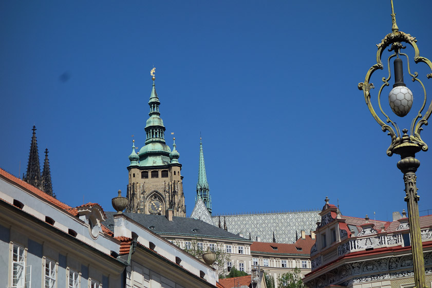 View of St. Vitus Cathedral from the square in front of St. Nicholas church in Malostranske Namesti. The two black towers are on the west front, and the large tower with clock is the south tower, begun in the 14c and topped in the 18c with a Baroque copper roof.