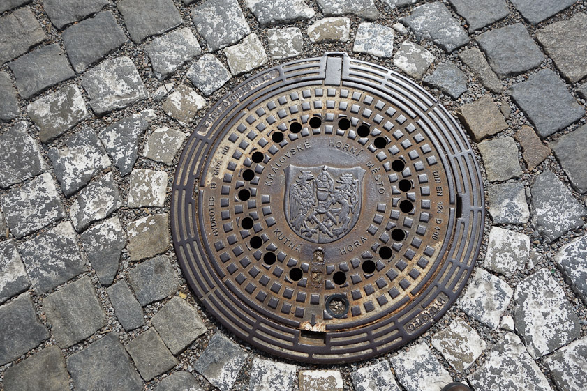 Manhole cover in Kutna Hora/. Th hammer and pck at the bottom were the tools of a silver miner, source of the town's prosperity.