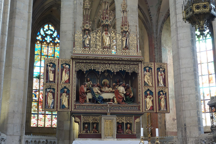 The altarpiece is 19c. The Jesuits had replaced the orginal when they redecorated in Baroque style after they took over in 1626. Restoration and reconstruction 1884-1905 presumably tried to return to Gothic style.