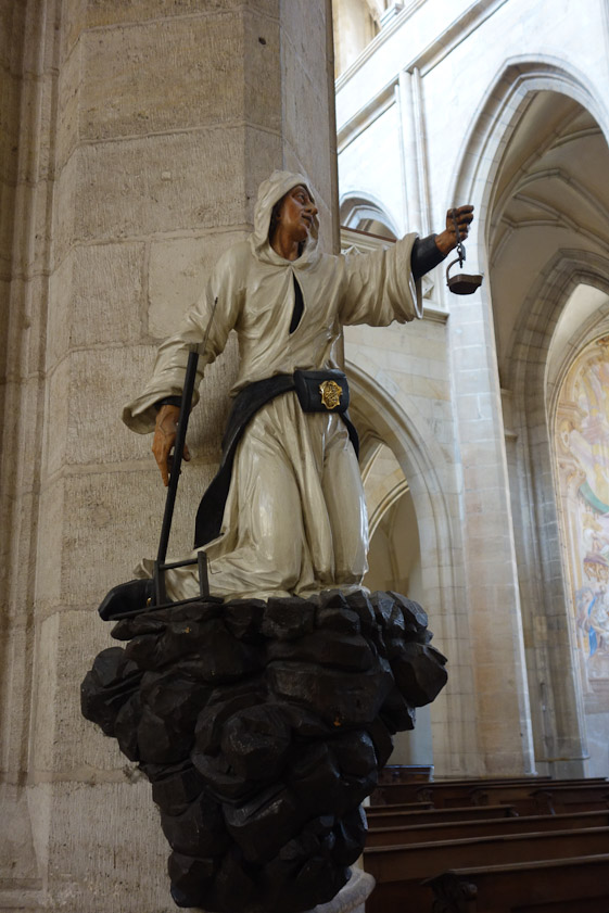 Painted wood figure of a miner from 1700. He holds a lamp in his left hand, and digging tool in his right. His leather apron in back is used to slide down into the mine.
