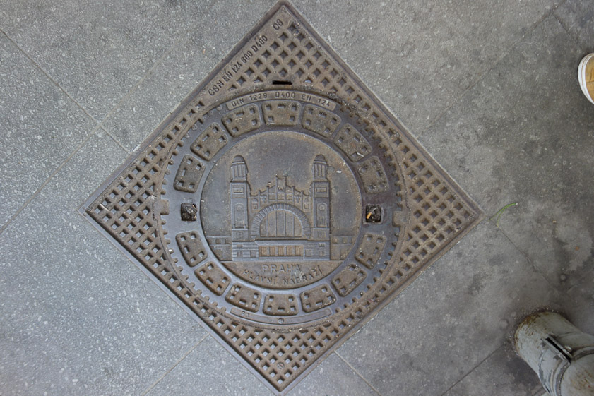The Prague manhole cover shows the train station