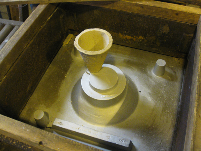 The cone defines the opening in the sand through which molten iron will be poured.