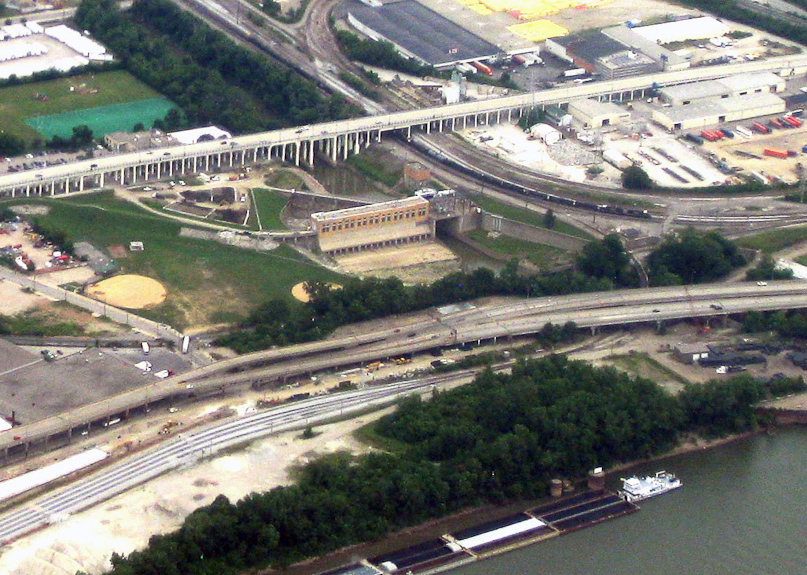This blown-up clip shows the flood control dam and pump house, the sand-colored building between the viaduct and the interstate.