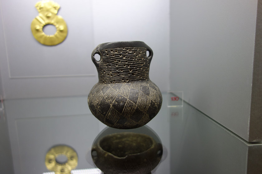 A hndled pot with a variety of decorative techniques including an irregular array of punched holes.