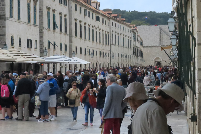 Toursists filling the Stradun, the main street of Dubrovnik. Before the 12c the area to te left was an island, Lausa, settled by refugees from Roman Epdaurum, which was destroyed by Avars and Slavs ca. 615. Slavs occupied the mainland, to the right. By the 12c the two settlements merged and the channel separating them was filled to form the present Stradun.
