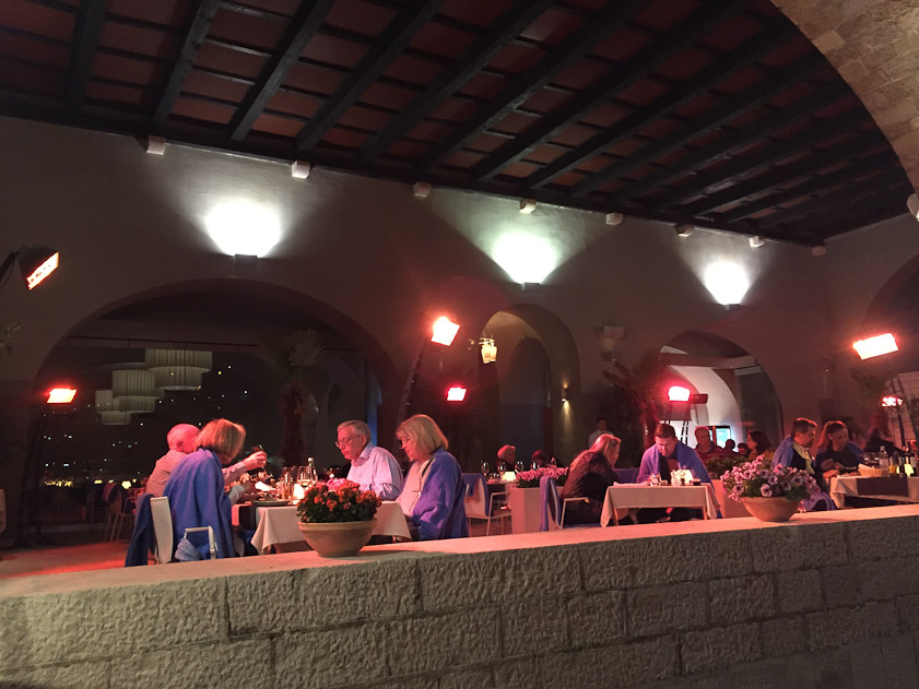 Another restaurant on the west side of the old harbor is bathed in the pink light of heaters.