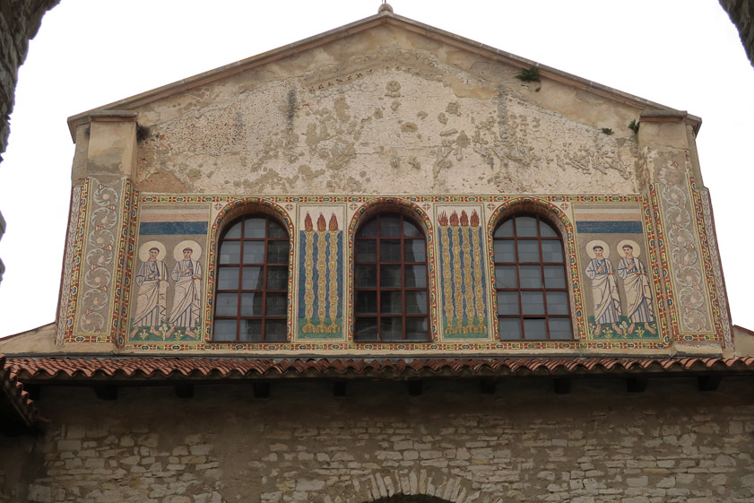 Windows in the basilica west wall alternate with mosaics.