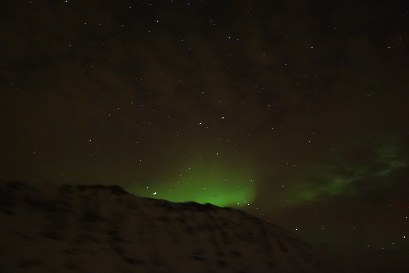 I took this photo at 9:40 PM on 22 January, an hour after leaving Tromsø. This was our first sight of the Northern Lights, and only with a time exposure of 5 seconds can you see the green color that distinguishes the Northern Lights from town lights reflected off clouds, which is red. Note the sky is black.