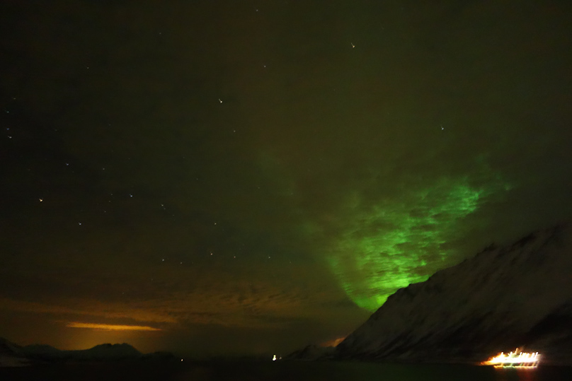 You can see clouds across the horizon, illuminated with town light on the left but by auroral display on the right. Note that street lighting in the lower right corner is saturated and blooming, unlike in the publicity picture.