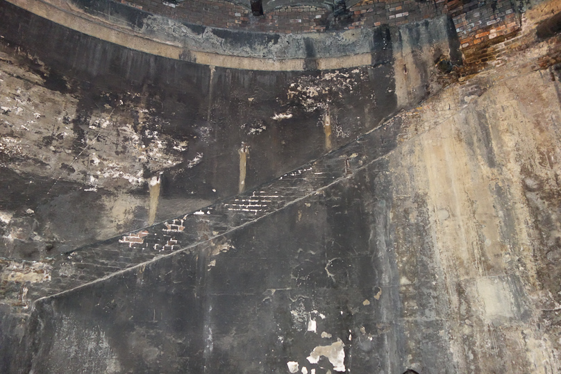 There used to be  a staircase spiraling down the inside of the cylinder. The black is soot from steam trains that passed through the entrance hall after the tunnel was put to use by the railroad in 1869. The original use was pedestrian..