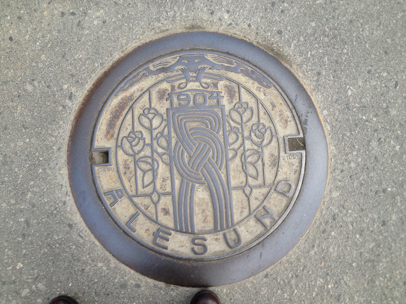 Manhole cover in Ålesund. The town was severely damaged by a fire in 1904 and rebuilt in Art Deco style, embodied in this stylized A.