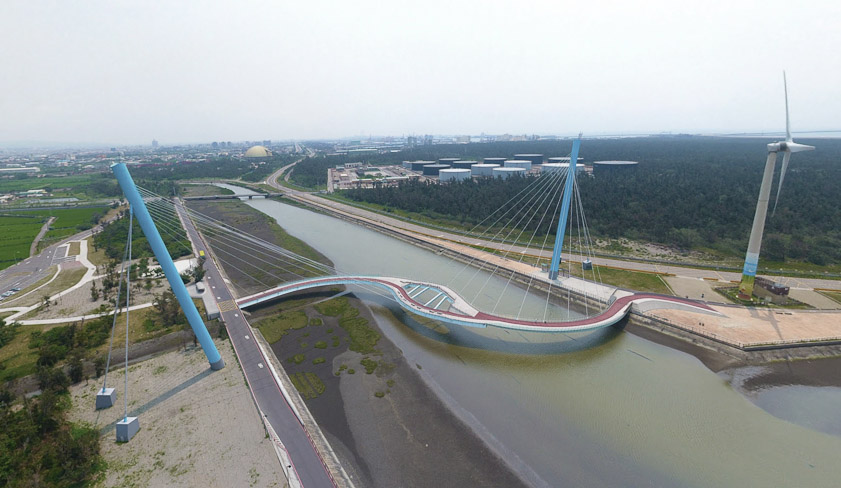 Another view taken from a drone above the east road, taken July 2017. A Google Street View from the west road (where the windmills are) taken December 2014 does not show the bridge, so it was built about 2005. It is a pedestrian bridge.