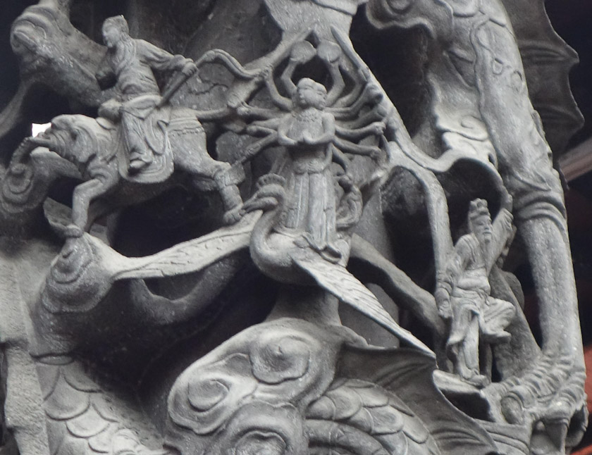 In the middle of the column, a figure with at least two faces and a dozen arms is standing on the back of a crested bird. A man to the left is riding an elephant. Another man is on the right next to one of the dragon's huge clawed legs.