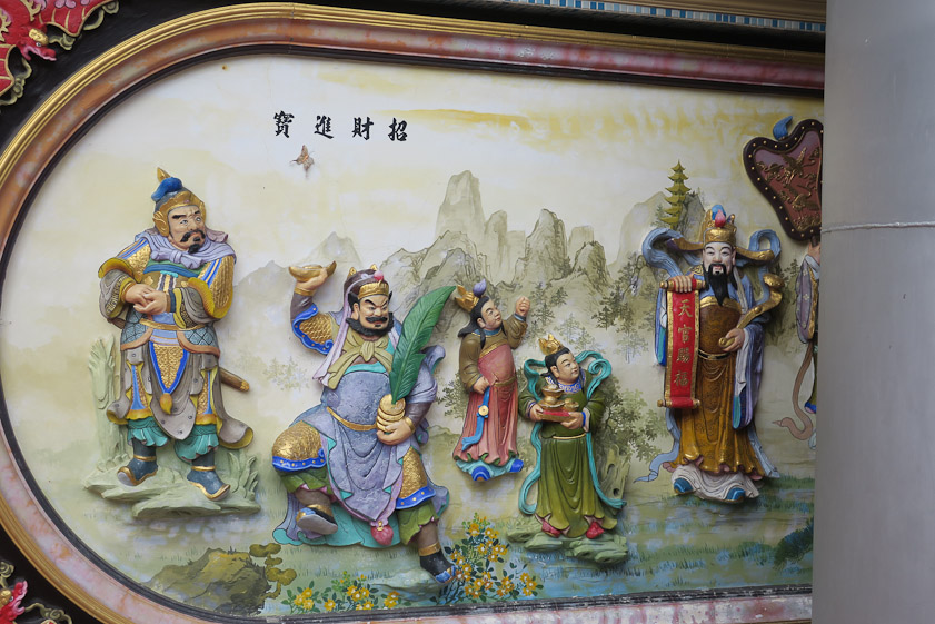 The figure at the right holds a scroll reading 