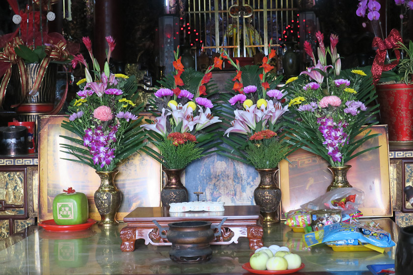 The altar with floral offerings and, at lower right, some packaged food and curious almost white fruit.