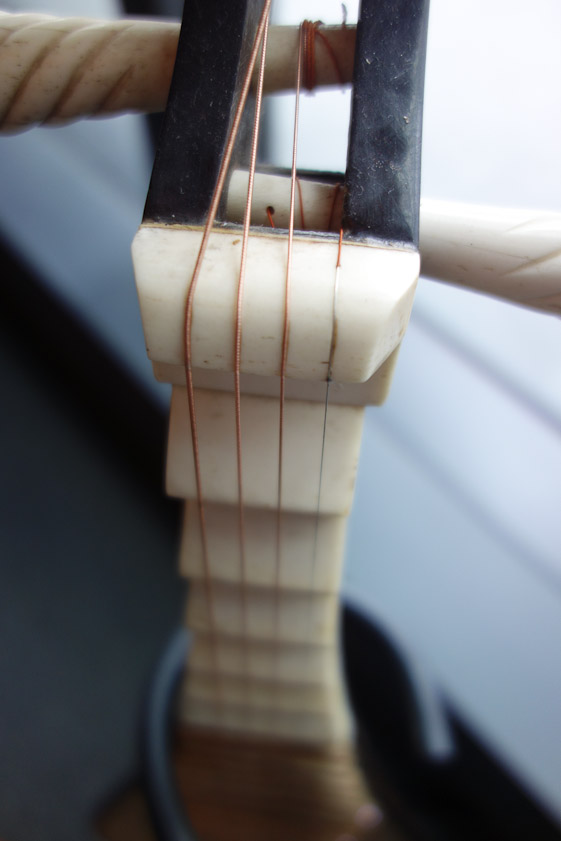 The pipa has four strings, three wound with wire like piano strings. The thickest winding (left) sounds the lowest note. The highest note (right) is sounded by the string without any winding.