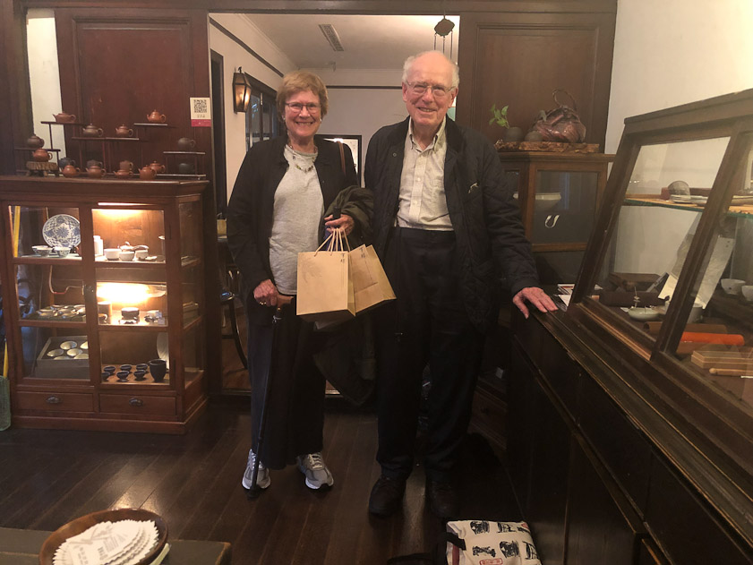 Happy customers departing with bags of tea and a tea pot