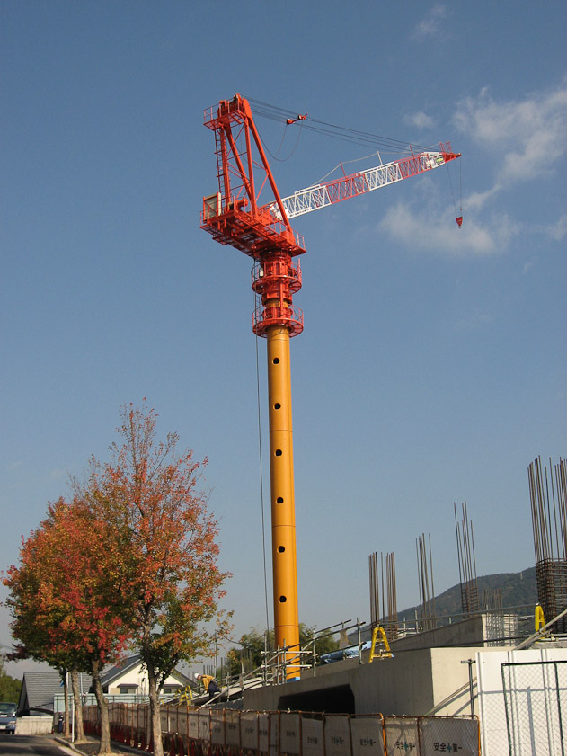 Japanese cranes are a different design from those used in the US. They have cylindrical towers rather than trestle work. This is a luffing jib, whereas the jibs on a US tower crane are fixed in a horizontal direction.