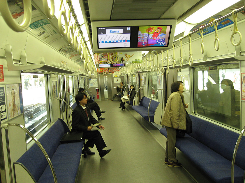 A subway car in Kyoto: wonderfully clean, with shelves where passengers can put their bags, and plenty of rings to steady standees. Note at least two large LED displays to give the train's current location and upcoming stations.