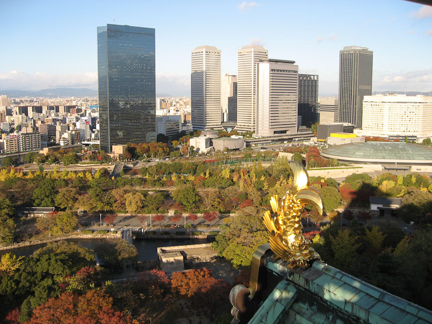 The view of modern Osaka from the top of the Castle, with the golden carp in the foreground.