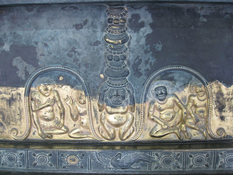 The figures on the pedestal, originally gilded, show grimacing beings.