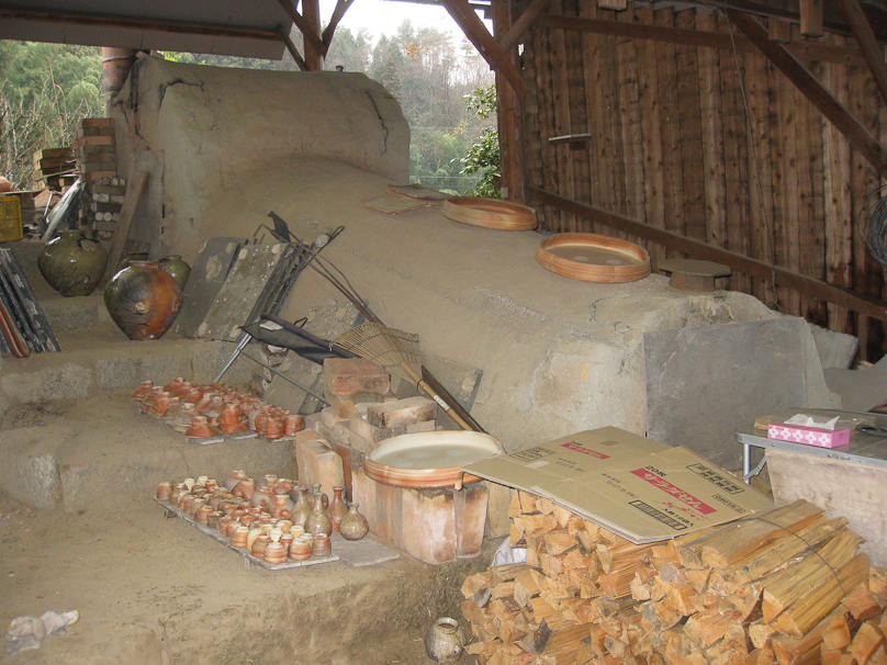This is Furutani's kiln witht the recently fired ware arrayed on the left and wood for the next firing in the foreground.