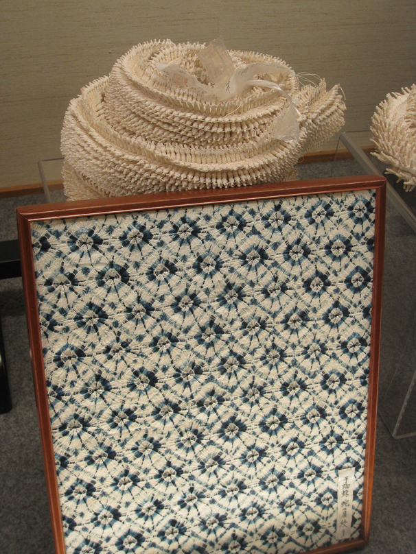 This display from the Arimatsu-Narumi Tie-Dyeing Museum  shows fabric that has been tied but not yet died on top of the dyed fabric after the ties have been removed.