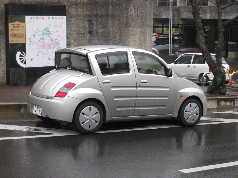This striking little car in Ueno, Mie Prefecture is representative of a huge number of similar size car we saw in Japan. While the Cooper Mini, the Fiat 500 and the Smart Car are just beginning to appear in the USA, that size is far more numberous in Japan, in many more models. This is a Toyota WiLL Vi, made 2000-2001.