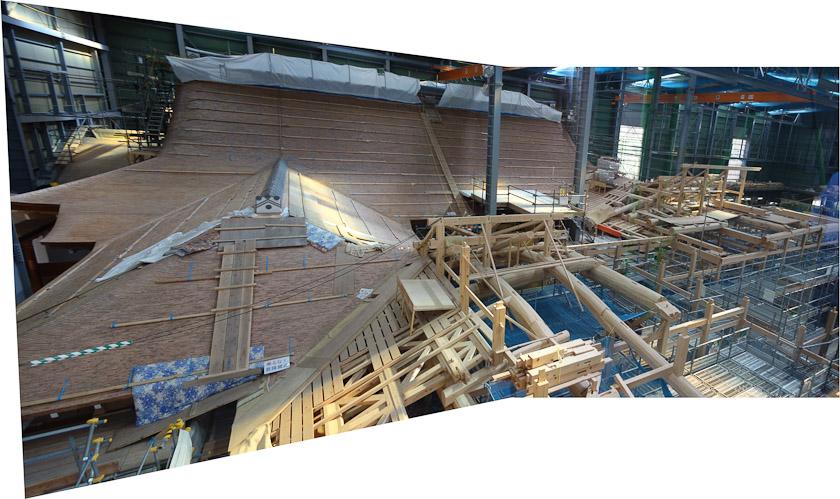 Mosaic of two photos taken inside the large shelter covering the reconstruction project. Such hanger-sized buildings are common in Japan when historic wooden temples and shrines are being rebuilt.