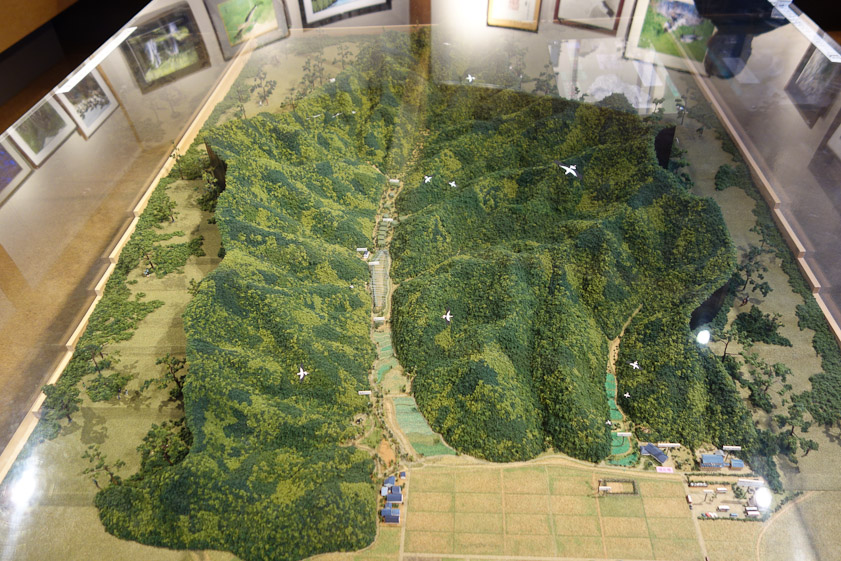 Model of the Homeland for the Oriental White Stork near Toyooka. The small valley on the right is terraced to form a staircase of ponds in which storks with clipped wings can feed. The visitor center is to the right of its mouth.