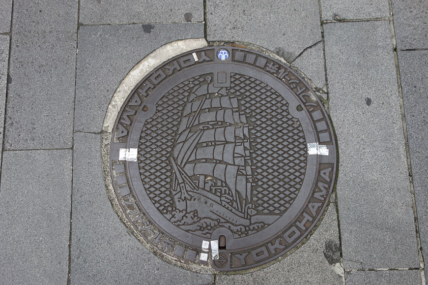 Manhole cover in Yokohama. The kanji on the bow read Nippon Maru backwards, the name of the four-masted sailing ship moored near our hotel.