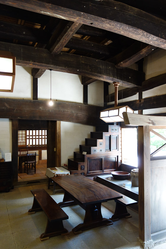Huge beams used to hold up he roof of a traditional Japanese farmhouse over lots of lovely, smooh wood furniture.