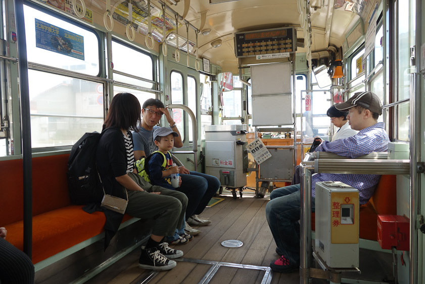 Interior of an old Hakodate streetcar. As on Japanese busses, passengers take a numbered ticket on boarding (from the machine with the yellow face) and pay the fare indicated by the display near the ceiling when dismounting.