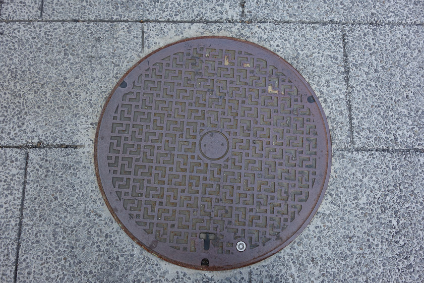 Manhole cover in Hirosaki. There's a pattern here, but I can't make it out. I suspect that it involves swastikas such as occur on other Hirosaki manhole covers.