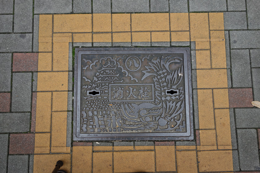 Manhole cover in Nagoya. The right side of the design echoes the carps at the corners of Nagoya Castle, shown at the left.