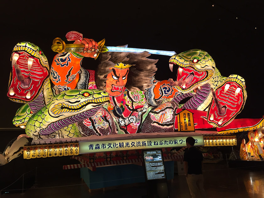 The hero is killing a demon with eight heads (only six appear here) to win the hand of a princess. You can see the scale of these floats from the dim visitor on the right.