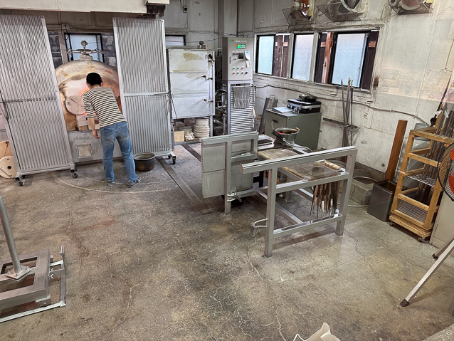 This is a glasss works where they teach glass working techniques. She is standing in front of a furnace where molten glass is kept.