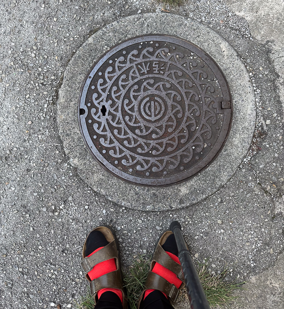 Manhole cover in Naha. Those are my socks designed by Jimmmy Onishi that we bought at the Ptrfectural Museum.