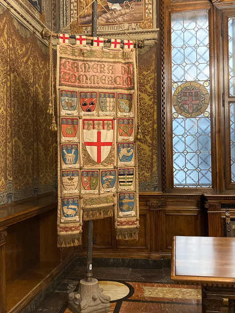 The Gonfalone contains the coats of arms of the 14 corporations of Bologna: Goldsmiths, Notaries, Drapers, Butchers, Woood workers, Apothecaries, Smiths, Sheath makers, Saddle makers, Sword makers. Painters, Dyers, Weavers, Fishmongers.