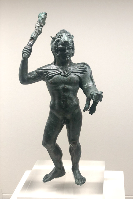 Herakles in the pose suggested by Polikleitrs, with left leg straight to bear the body's weight and the right bent outwards. The right arm, raised, wields a club and the hand stretch forward, holds out the golden apples of Hesperides, stolen as one of the 