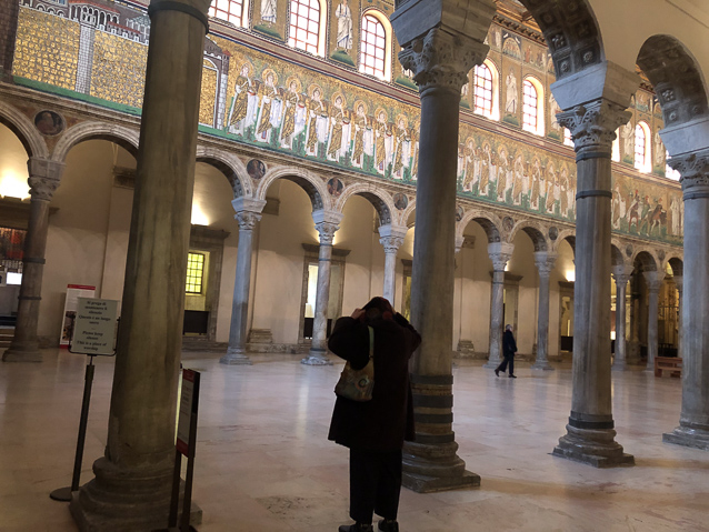 The church was built as the chapel of Thedoric's palace in 504 AD. It was redecorated as an orthodox church in the time of Justinian and reconsecrated in 561. The  principal decoration of the interior are mosaics in three ranks on the north and south walls..The bottom rank on the north wall, seen here, is from the time of Justinian and is a processon of female martyrs. Above them are figures of saints between widnows. At the top rank are scenes from the life of Christ. The two higher ranks are from Theodoric's time.