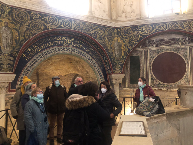 A tour group was securely masked. At the right is a full immersion font. The niches and wall decorations were part of the Roman bath.