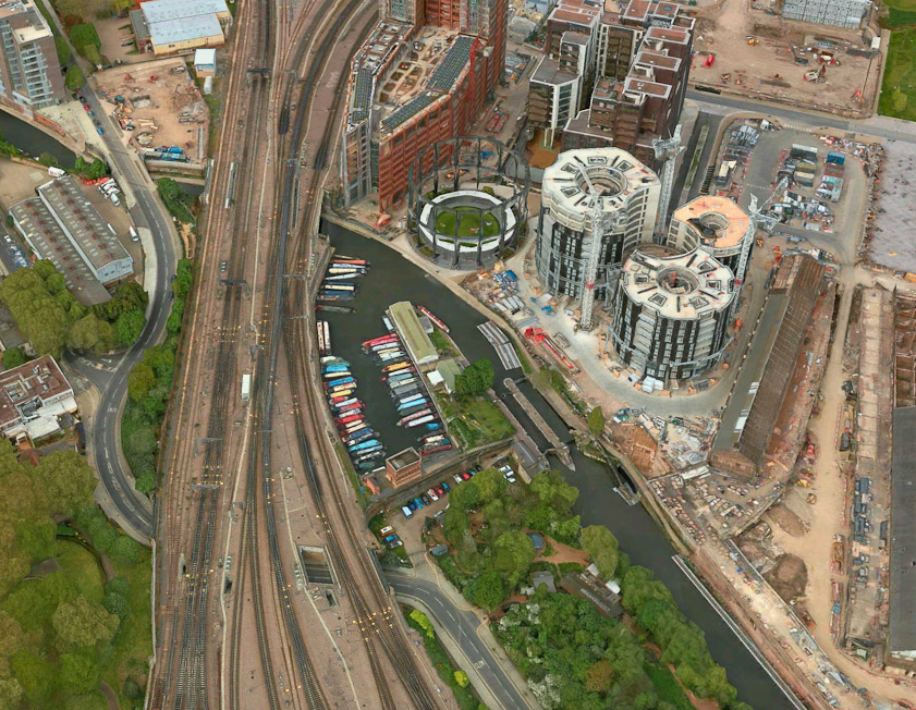 An aerial view of that sceene, from Apple Maps. That is Regent's Canal and the development is called Gasholder Park . It is described here: http://www.architectmagazine.com/project-gallery/gasholder-park_o