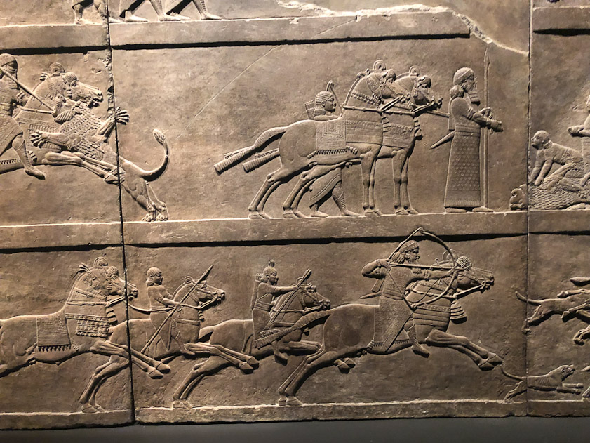 The top register shows a lion hunt; the bottom shows a ibex hunt.