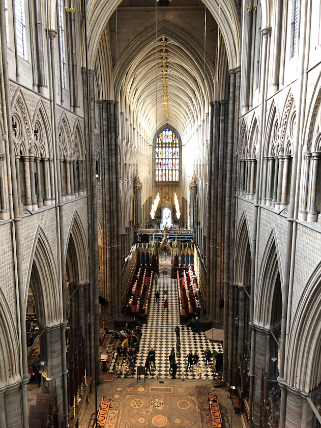 View to the west from the triforium. In the foreground at the bottom is the Cosmati pavement installed by Henry III (1207-72). Further west is the crossing, then the choir, a screen, and the nave up to the west door. The arches of the triforium are between the clerestory windows and the arches of the ambulatory.