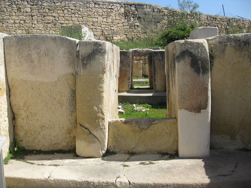 Several apses at Tarxien connected by a central corridor, with an obstacle (faint spiral design) hindering access.
