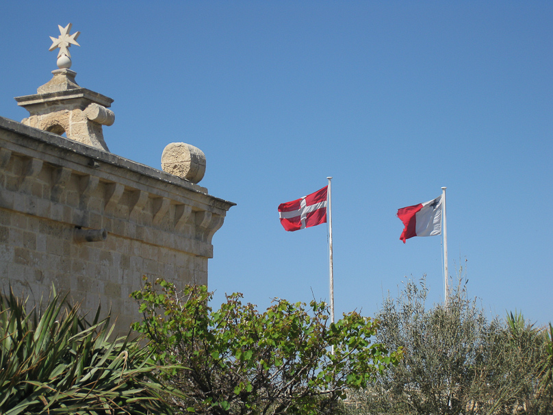 The Maltese flag is on the right, the flag of the Order of Knights of St. John is on the left.
