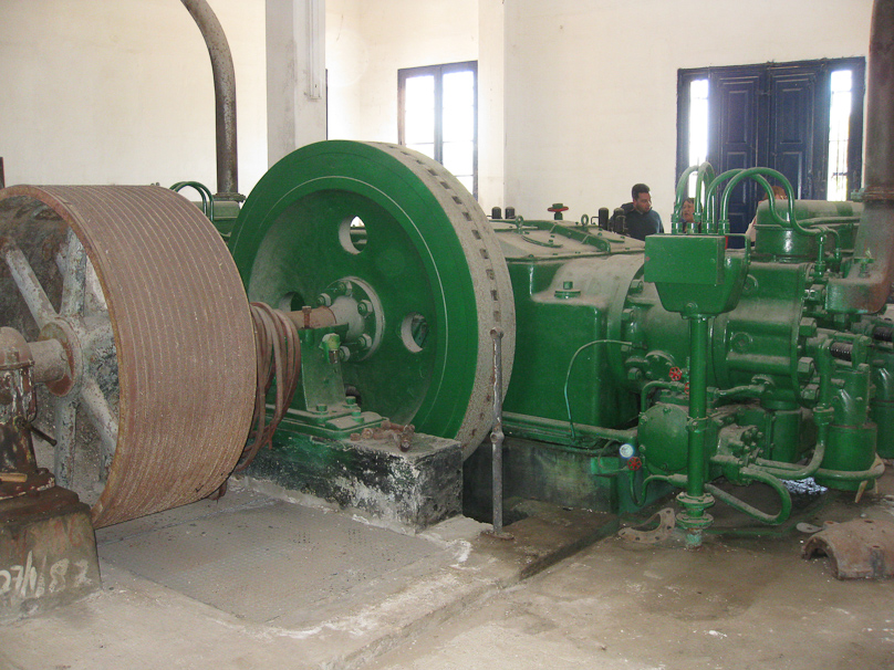 The diesel engine is in the back on the right, its flywheel in the center, and the pulley that drove multiple belts to supply power to the underground pumps is at the left.