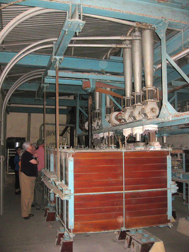 These are sieves, to separate the output of the mills into eight different size particle. They are shaken side to side when in operation, and eight different size particles come out openings in the bottom.