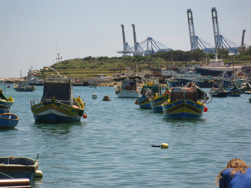 Around the bay from the picturesque fishing village is Malta Freeport. Those appear to be container cranes.